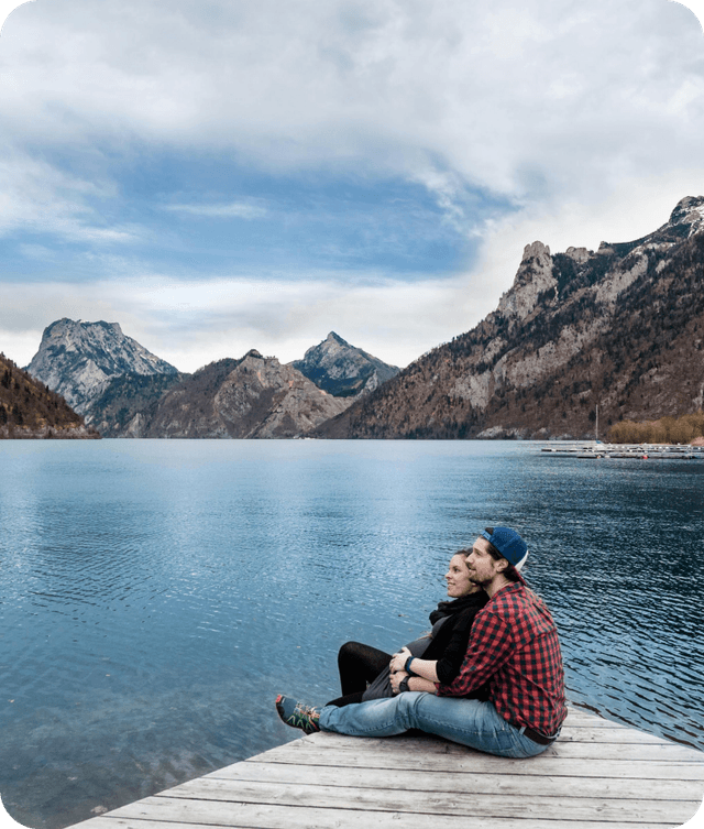 Couple sitting on dock with mountain lake background