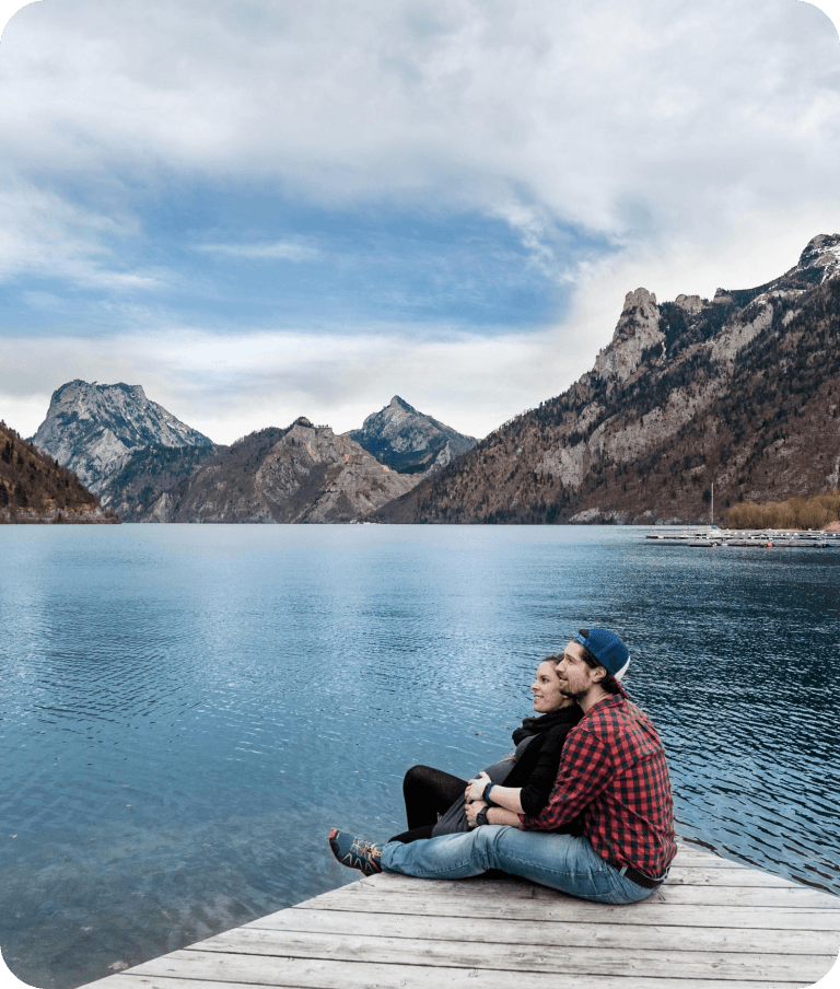 Couple sitting on dock with mountain lake background